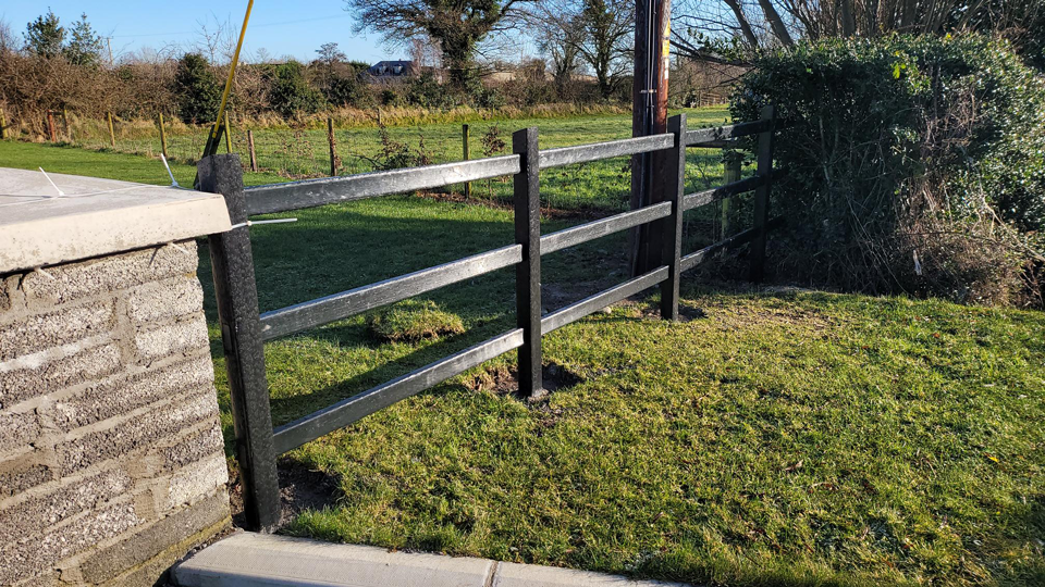 plastic fence installed in a garden beside a stone gate pillar